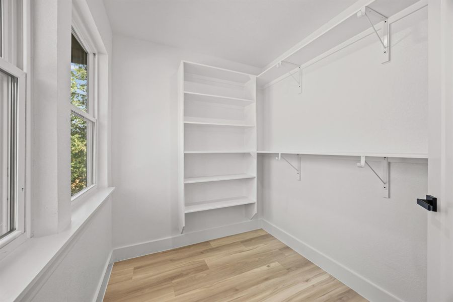 Spacious primary bedroom closet featuring light wood-type flooring