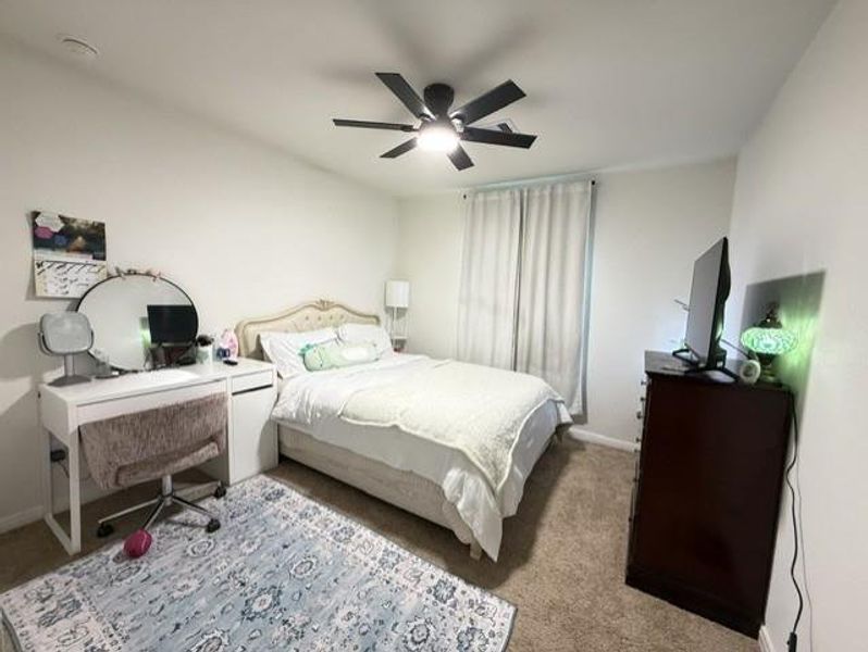 Well-sized secondary bedroom featuring carpet flooring, modern ceiling fan, and a bright window — a great space for guests or family Well-sized secondary bedroom featuring carpet flooring, modern ceiling fan, and a bright window — a great space for guests or family