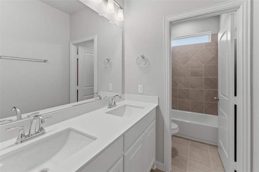 Bathroom featuring a double vanity with integrated sinks, chrome fixtures, and a large mirror Bathroom featuring a double vanity with integrated sinks, chrome fixtures, and a large mirror