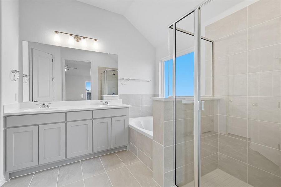 Full bathroom featuring a garden tub, a stall shower, vaulted ceiling, double vanity, and light tile patterned floors Full bathroom featuring a garden tub, a stall shower, vaulted ceiling, double vanity, and light tile patterned floors