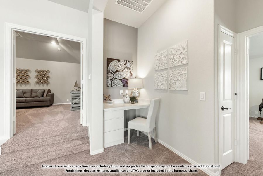 Hallway with built-in desk nook and white chair, opening to carpeted living room with sofa beyond Hallway with built-in desk nook and white chair, opening to carpeted living room with sofa beyond