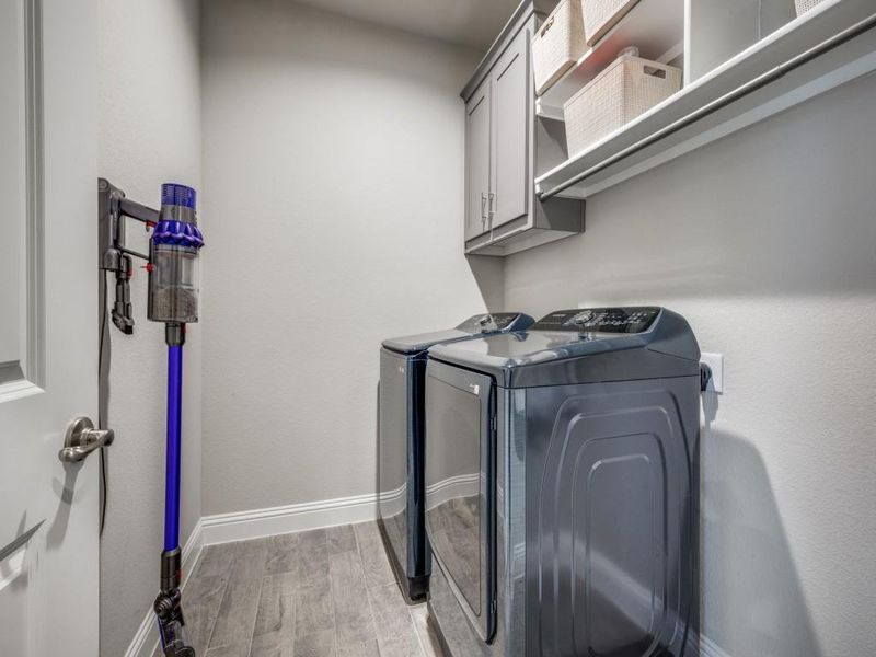 Practical and well-organized laundry room featuring extra storage and a hanging rack!