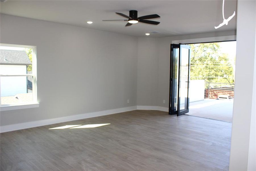 Unfurnished room featuring ceiling fan, wood-type flooring, and plenty of natural light