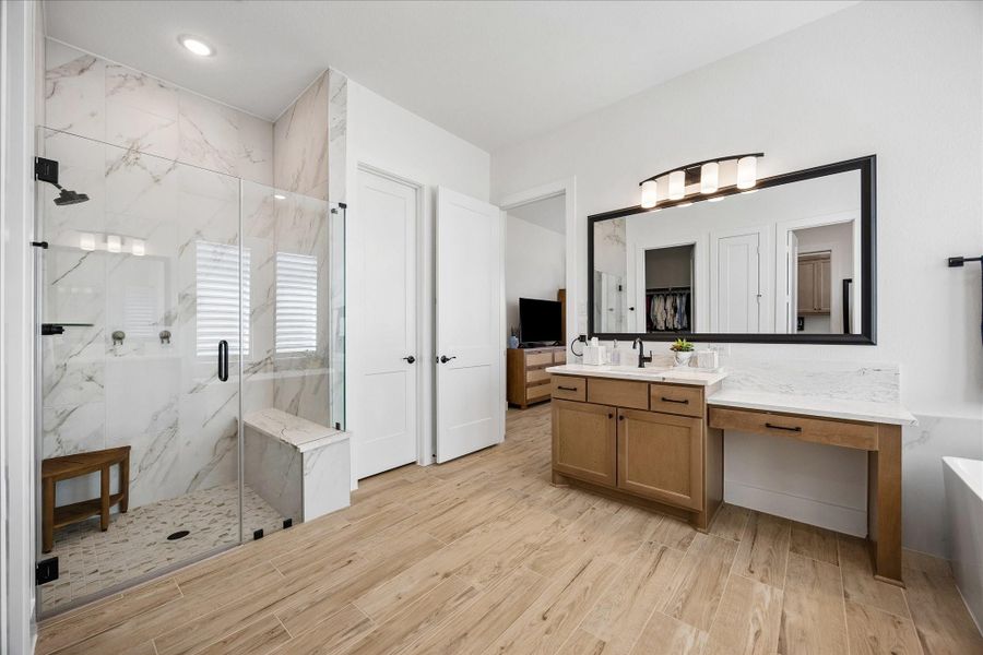 The primary bathroom features a luxurious upgraded frameless glass shower with marble tile, modern matte black fixtures and a built-in bench. The suite also includes a private toilet room and spacious his-and-hers walk-in closets.
