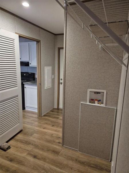 Laundry room with crown molding, light wood-type flooring, and cabinet space