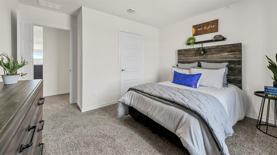 Carpeted bedroom featuring a rustic wood headboard with an integrated sconce light, white walls, and a contemporary door