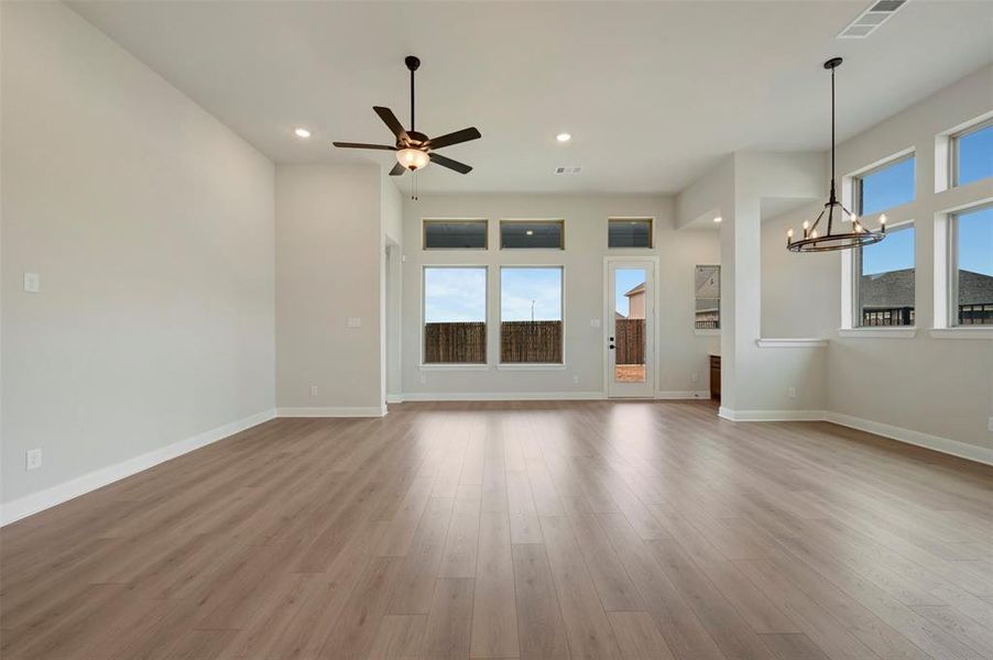 Unfurnished living room featuring hanging lights, healthy amount of natural light, light wood-type flooring, and ceiling fan