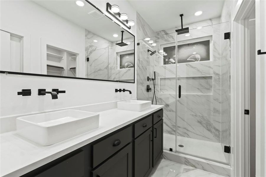 Bathroom featuring light marble finish floors, double vanity, a marble finish shower, and recessed lighting