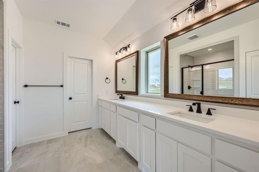 Bathroom featuring double vanity, a tile shower, and marble finish floors Bathroom featuring double vanity, a tile shower, and marble finish floors