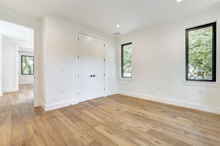 Unfurnished bedroom with multiple windows, light wood-type flooring, baseboards, and recessed lighting