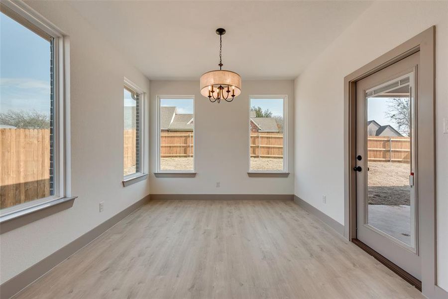 Unfurnished dining area featuring a notable chandelier, a healthy amount of sunlight, and light wood-type flooring