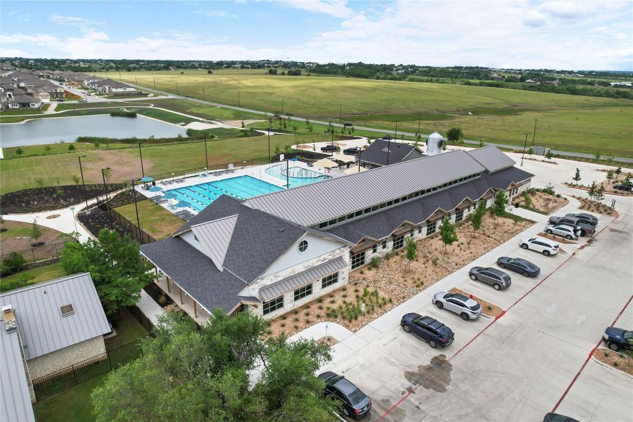 An aerial view captures the vibrant community hub, showcasing a modern clubhouse adjacent to inviting swimming pools.