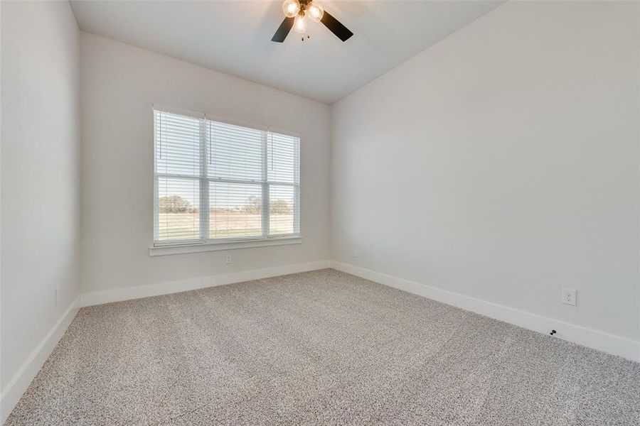 Carpeted empty room with ceiling fan and lofted ceiling