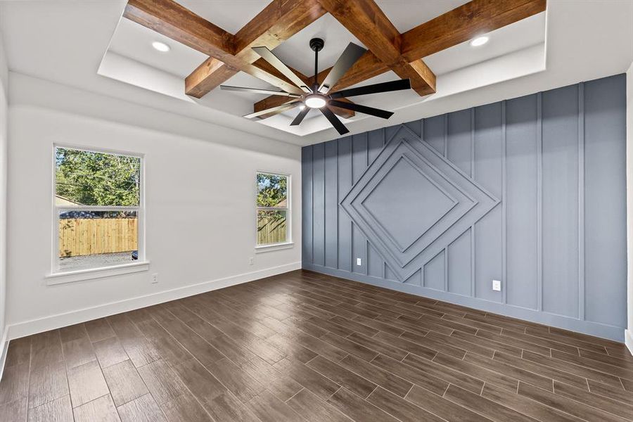 Unfurnished room with coffered ceiling, beam ceiling, dark wood-type flooring, ceiling fan, and a decorative wall Unfurnished room with coffered ceiling, beam ceiling, dark wood-type flooring, ceiling fan, and a decorative wall