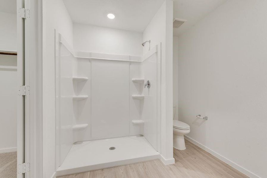 Bathroom featuring hardwood / wood-style flooring, toilet, and walk in shower