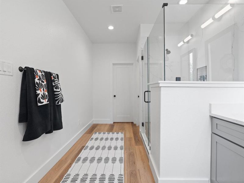 Full bathroom featuring visible vents, a marble finish shower, wood finished floors, and vanity