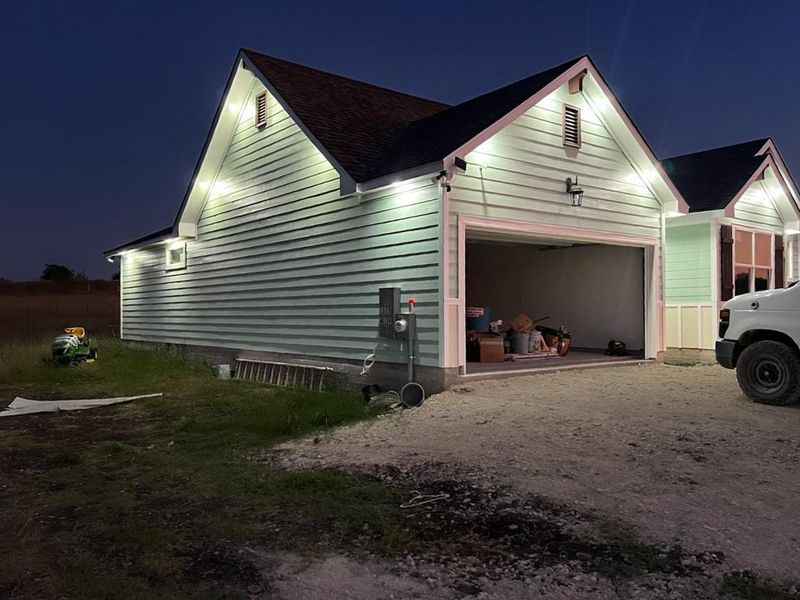 Property exterior at night with an attached garage and driveway