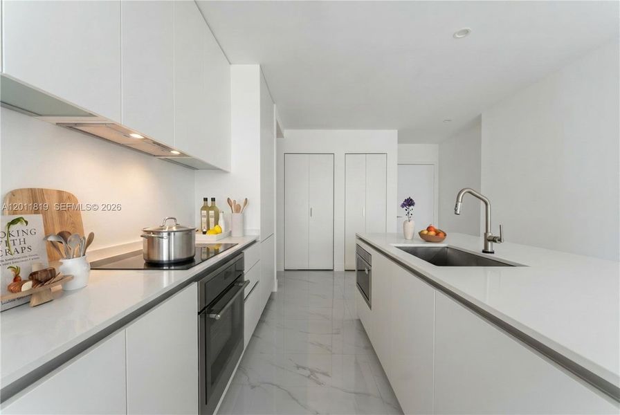 Modern chef’s kitchen equipped with custom Italian cabinetry, premium Miele appliances, integrated stone countertops, and a waterfall island perfect for entertaining. Image i virtually staged.