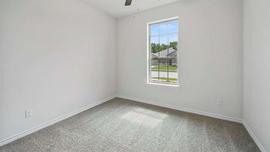 Carpeted spare room featuring a ceiling fan and baseboards