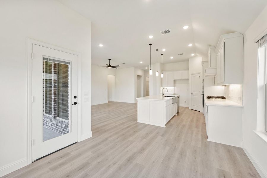 Open-concept kitchen and living area with white cabinets, center island, pendant lights, and light wood floors Open-concept kitchen and living area with white cabinets, center island, pendant lights, and light wood floors
