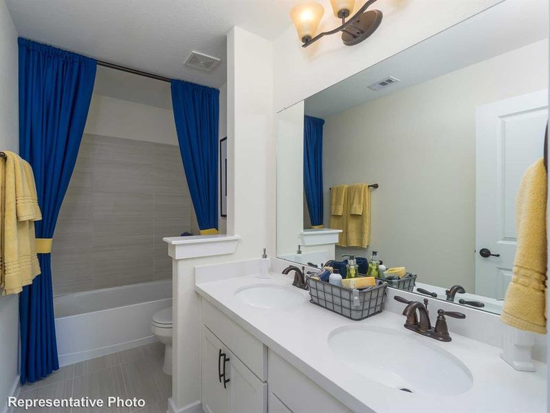 Bathroom featuring double vanity, shower / bath combo with shower curtain, and light tile patterned flooring