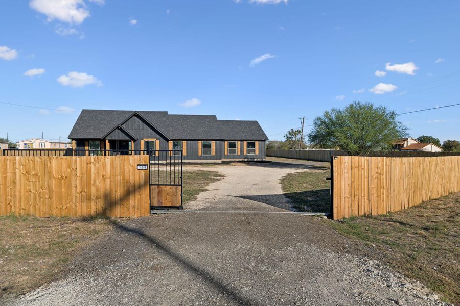 View of front of property with a fenced front yard, a gate, driveway, and a shingled roof View of front of property with a fenced front yard, a gate, driveway, and a shingled roof