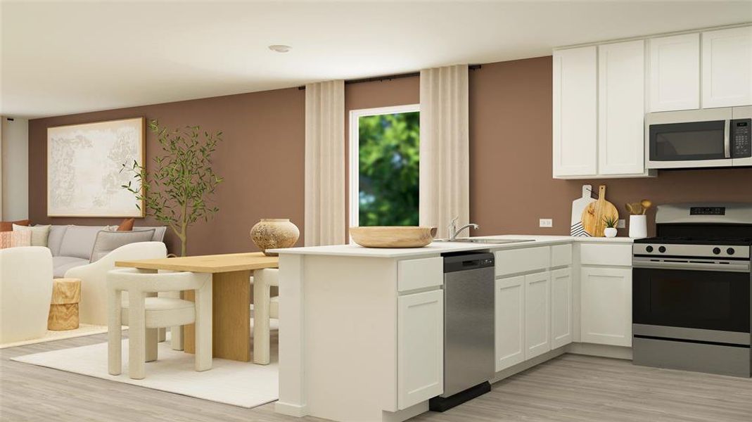 Kitchen with open floor plan, stainless steel appliances, light countertops, white cabinetry, and a sink