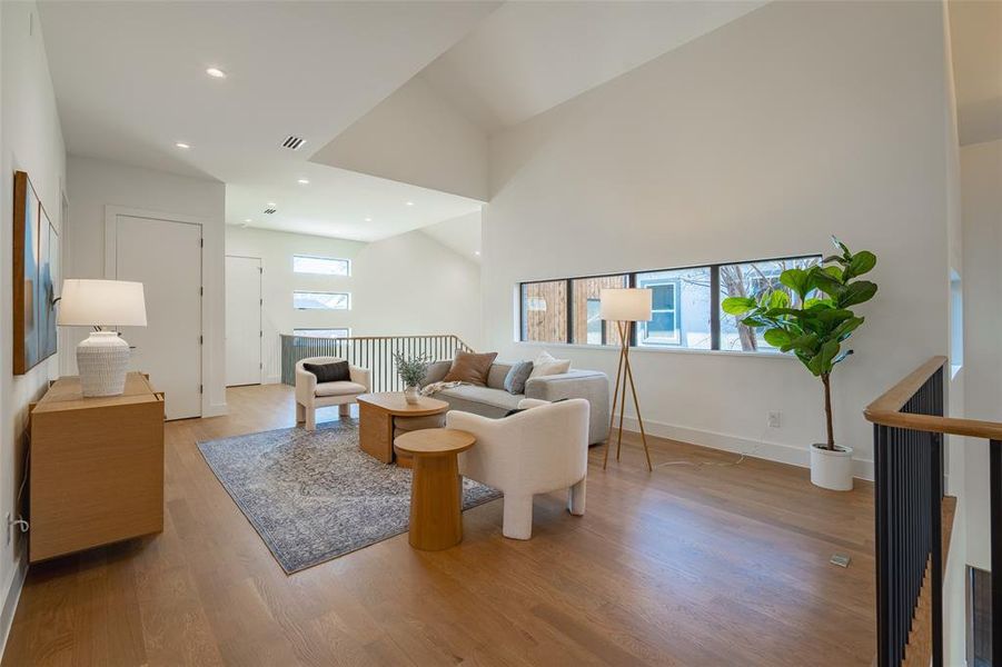 Living room with lofted ceiling and light hardwood / wood-style floors