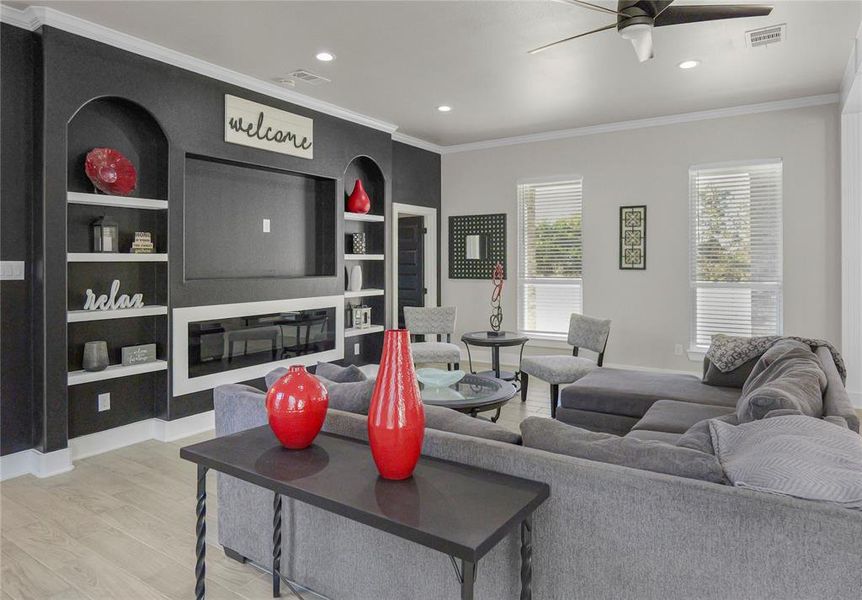 Living area with crown molding, light wood-style flooring, recessed lighting, built in features, and ceiling fan