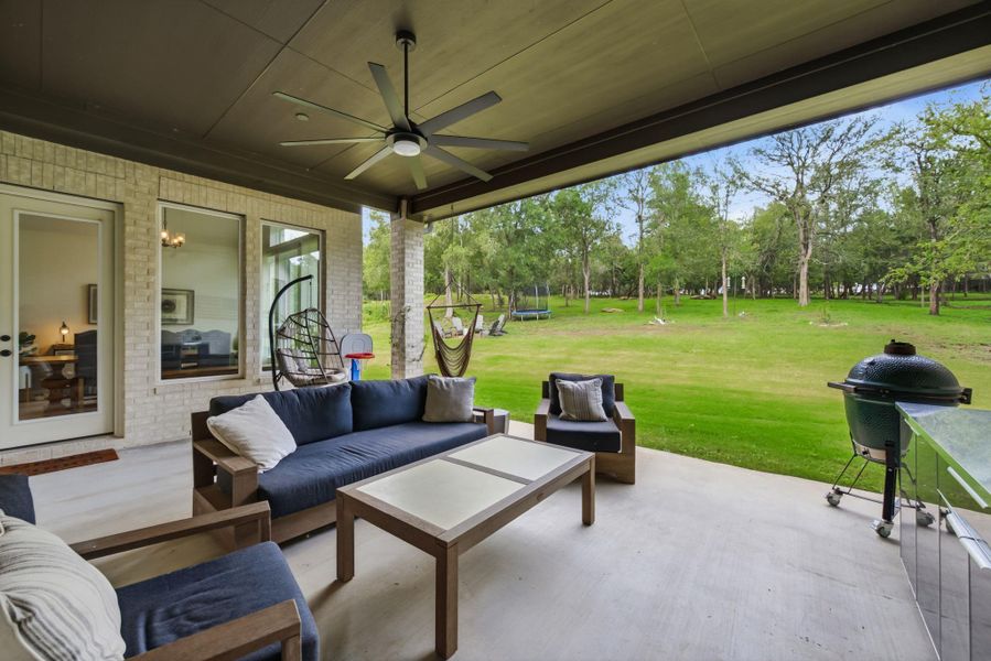 The large covered back patio is designed for seamless indoor-outdoor living, providing a shady, comfortable spot to grill, dine, or just listen to the wind through the trees