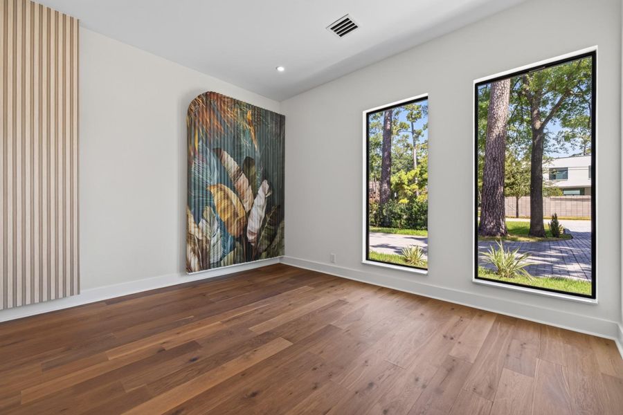 Guest bedroom offers hardwood flooring, natural light and views of the landscaped property.