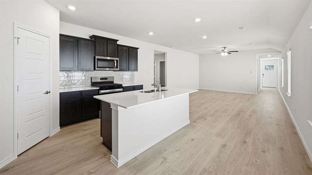 Kitchen featuring a center island with sink, decorative backsplash, appliances with stainless steel finishes, recessed lighting, and light wood-type flooring