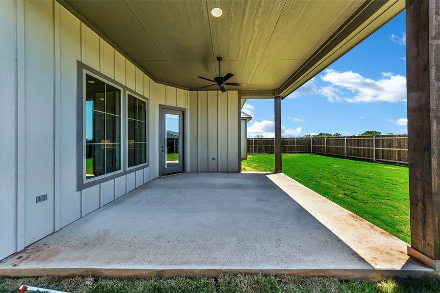 Fenced backyard with a ceiling fan and a patio