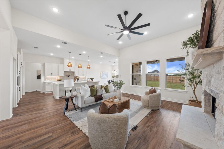 Living area featuring dark wood-style flooring, a stone fireplace, recessed lighting, and ceiling fan Living area featuring dark wood-style flooring, a stone fireplace, recessed lighting, and ceiling fan