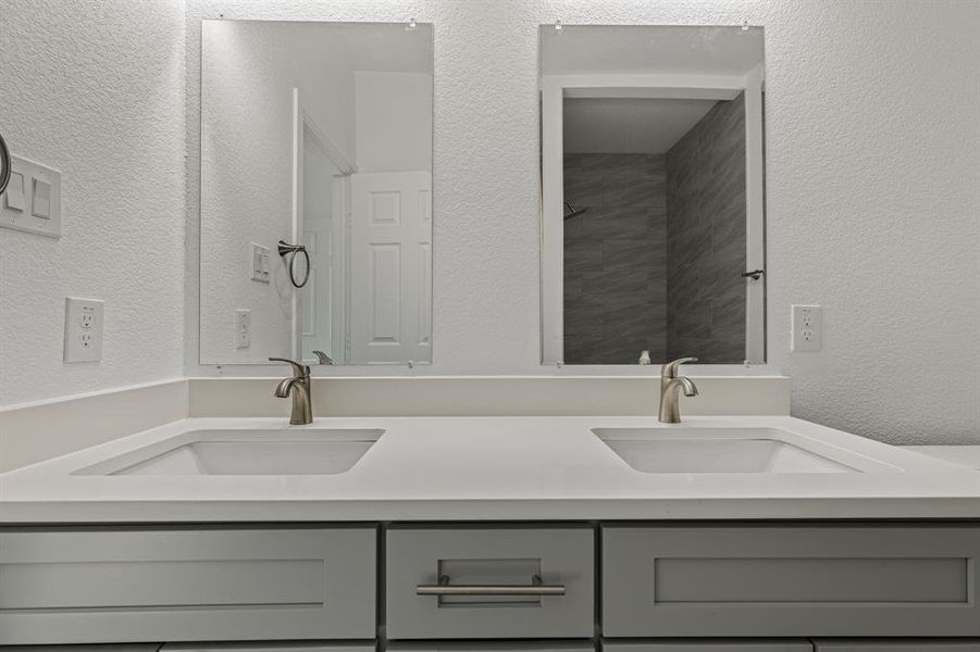 Full bath with a textured wall and double vanity