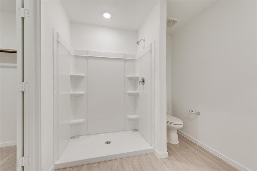 Bathroom with a shower, hardwood / wood-style floors, and toilet