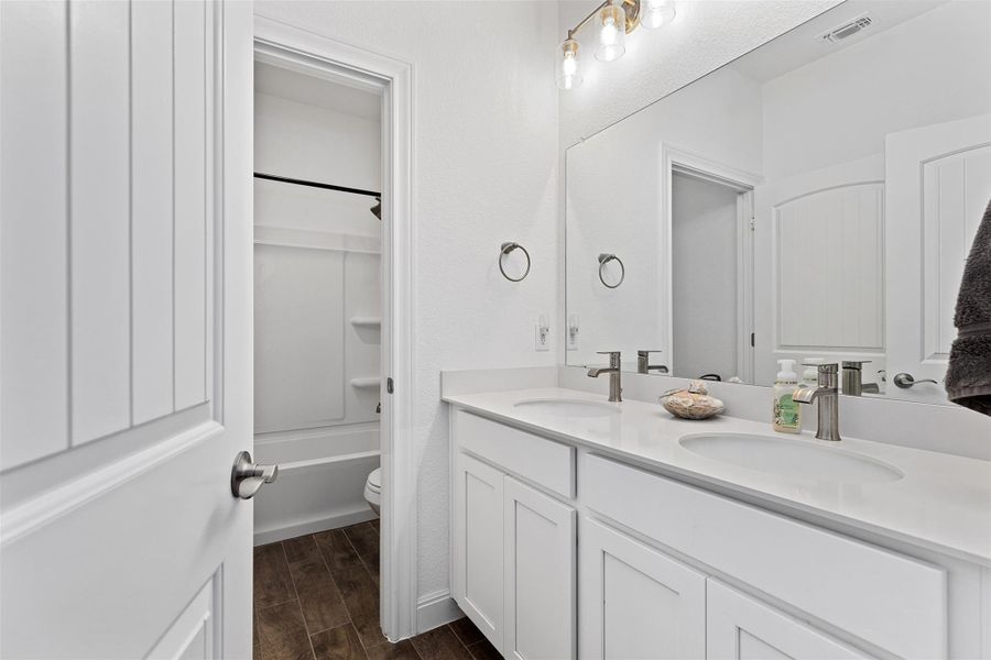 Full bathroom with double vanity, wood tiled floors, and shower / bathtub combination