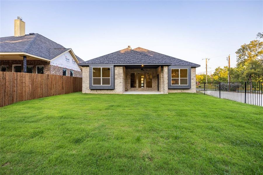 Rear view of house with a chimney, a shingled roof, a patio, a fenced backyard, and brick siding