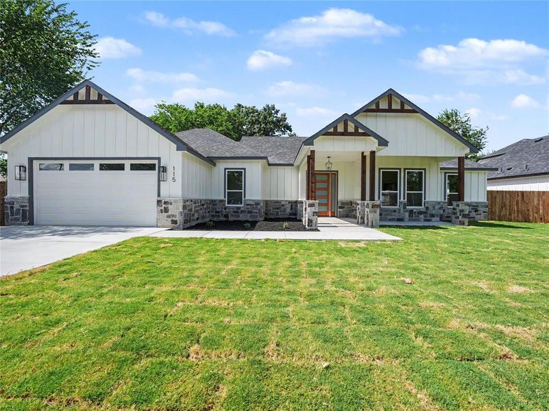 Craftsman-style exterior featuring board and batten siding, stone facade, covered porch with wood columns, and a two-car garage with transom windows Craftsman-style exterior featuring board and batten siding, stone facade, covered porch with wood columns, and a two-car garage with transom windows