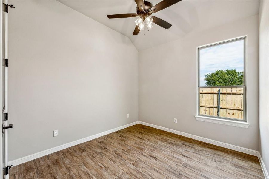 Unfurnished room featuring vaulted ceiling, plenty of natural light, light hardwood / wood-style flooring, and ceiling fan