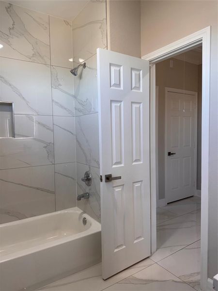 Elegant bathroom featuring a sleek bathtub with contemporary marble-style tile, adding a touch of luxury. Elegant bathroom featuring a sleek bathtub with contemporary marble-style tile, adding a touch of luxury.