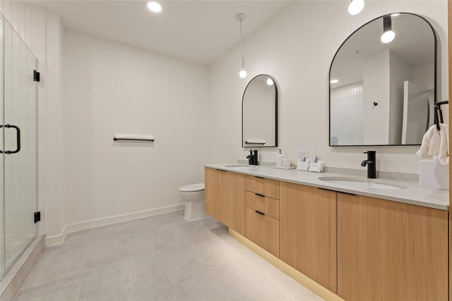 Clean lines and a spacious double vanity anchor this modern bathroom featuring tiled flooring. Clean lines and a spacious double vanity anchor this modern bathroom featuring tiled flooring.