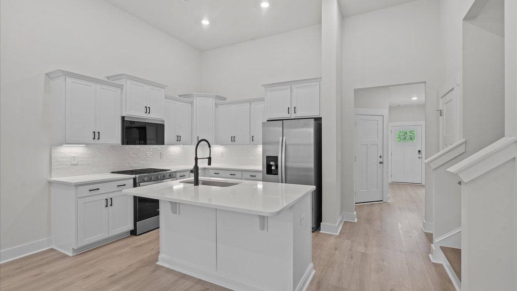 Two story ceiling kitchen with white cabinetry and modern black accents in two story townhome at Aspen Ridge by DRB Homes Two story ceiling kitchen with white cabinetry and modern black accents in two story townhome at Aspen Ridge by DRB Homes