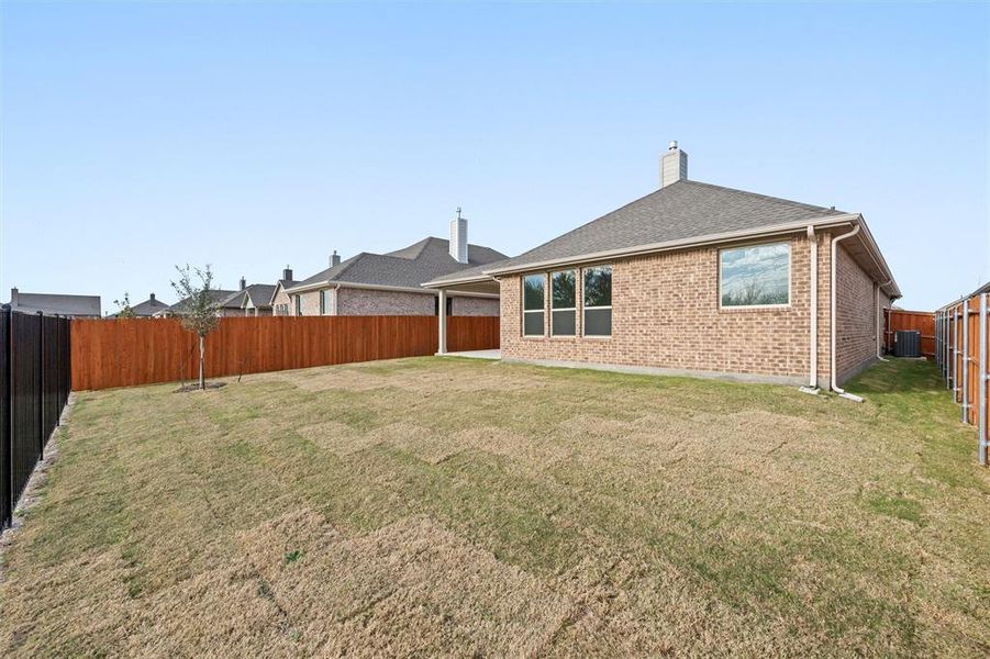 Rear view of house with brick siding, a chimney, a fenced backyard, a patio, and a shingled roof