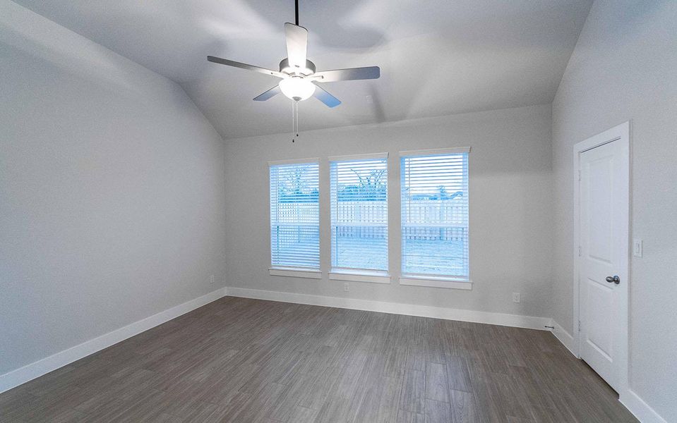 Spare room with a ceiling fan, baseboards, vaulted ceiling, and dark wood-style flooring
