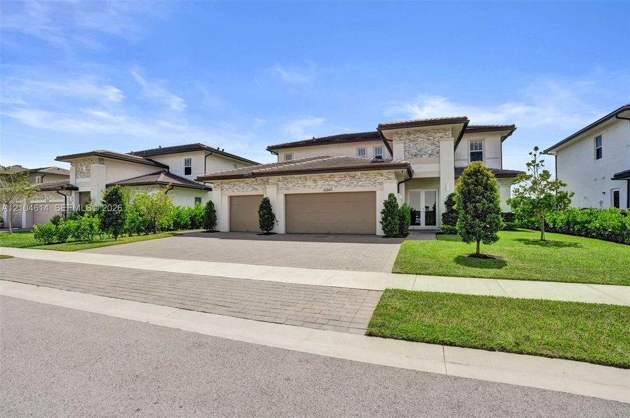 Contemporary-style residence featuring a textured stone facade and a paver driveway
