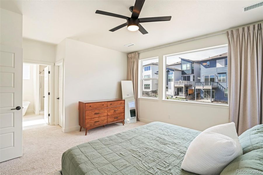 Spacious primary bedroom with large windows and natural light, offering a peaceful retreat with foothill views in this Three Hills home