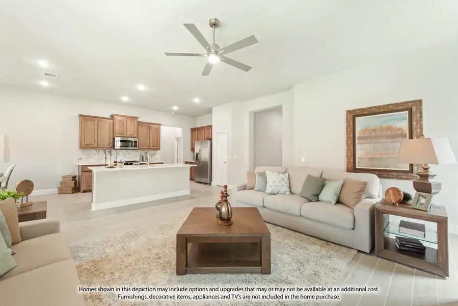Open-concept living room with ceiling fan and kitchen featuring wood cabinets and stainless appliances in background Open-concept living room with ceiling fan and kitchen featuring wood cabinets and stainless appliances in background