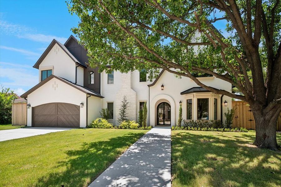 Maison Manor Homes new construction, stucco and stone facade, arched iron entry, wood-panel garage door Maison Manor Homes new construction, stucco and stone facade, arched iron entry, wood-panel garage door