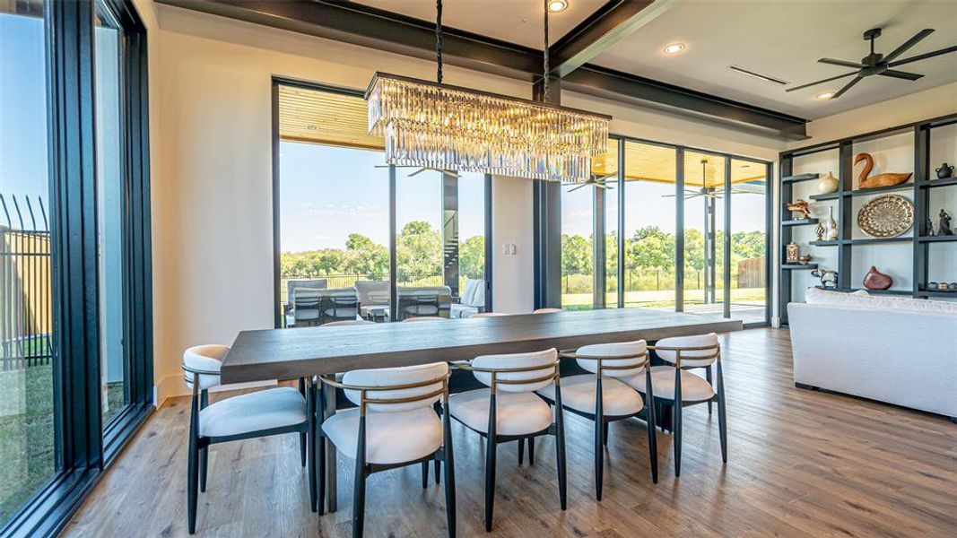 Dining room featuring beamed ceiling, ceiling fan with notable chandelier, and hardwood / wood-style flooring